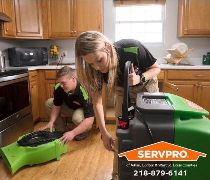 Technicians install air blowers in a water-damaged kitchen.