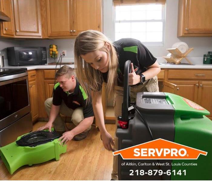 SERVPRO technicians set up drying equipment in a kitchen damaged by water.
